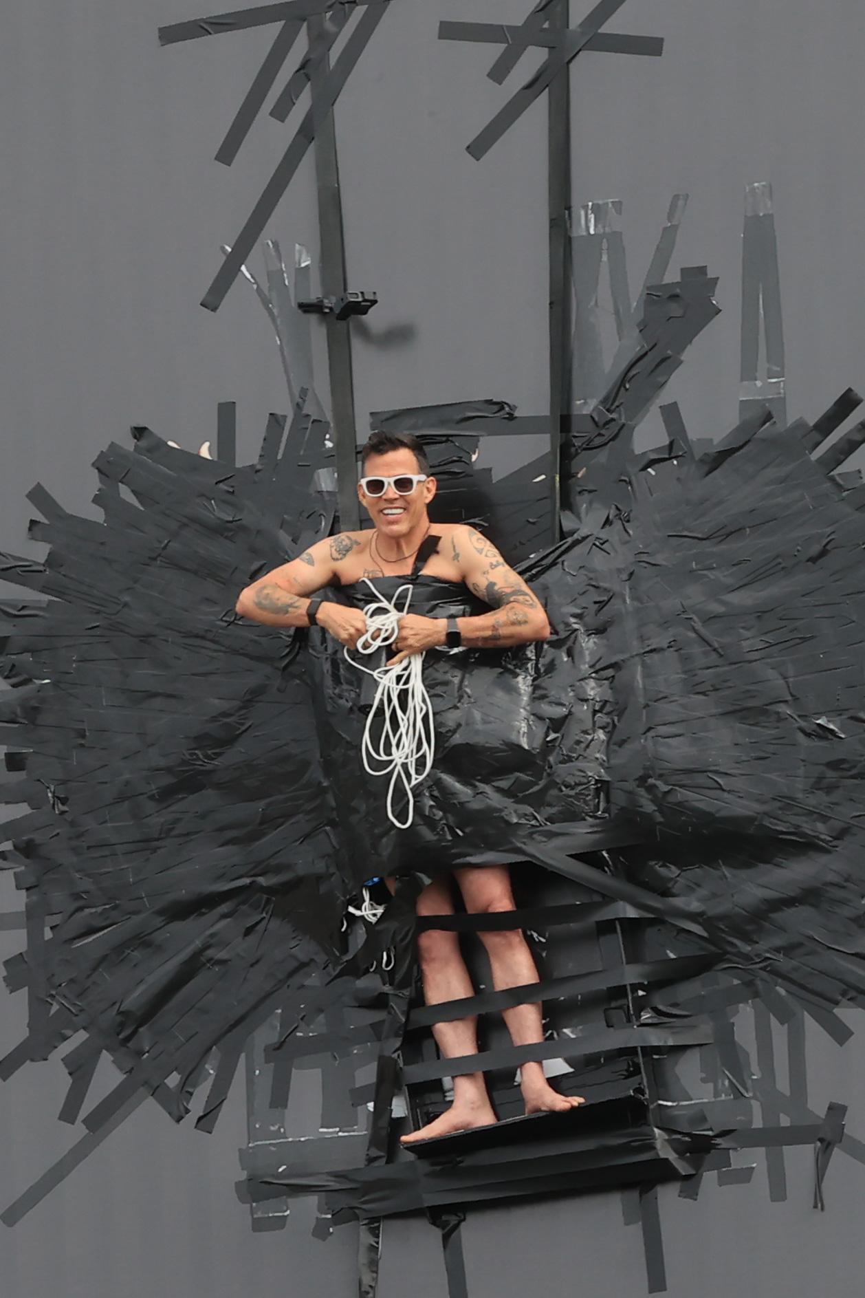 Steve O is helped down by emergency services after duct taping himself to a billboard