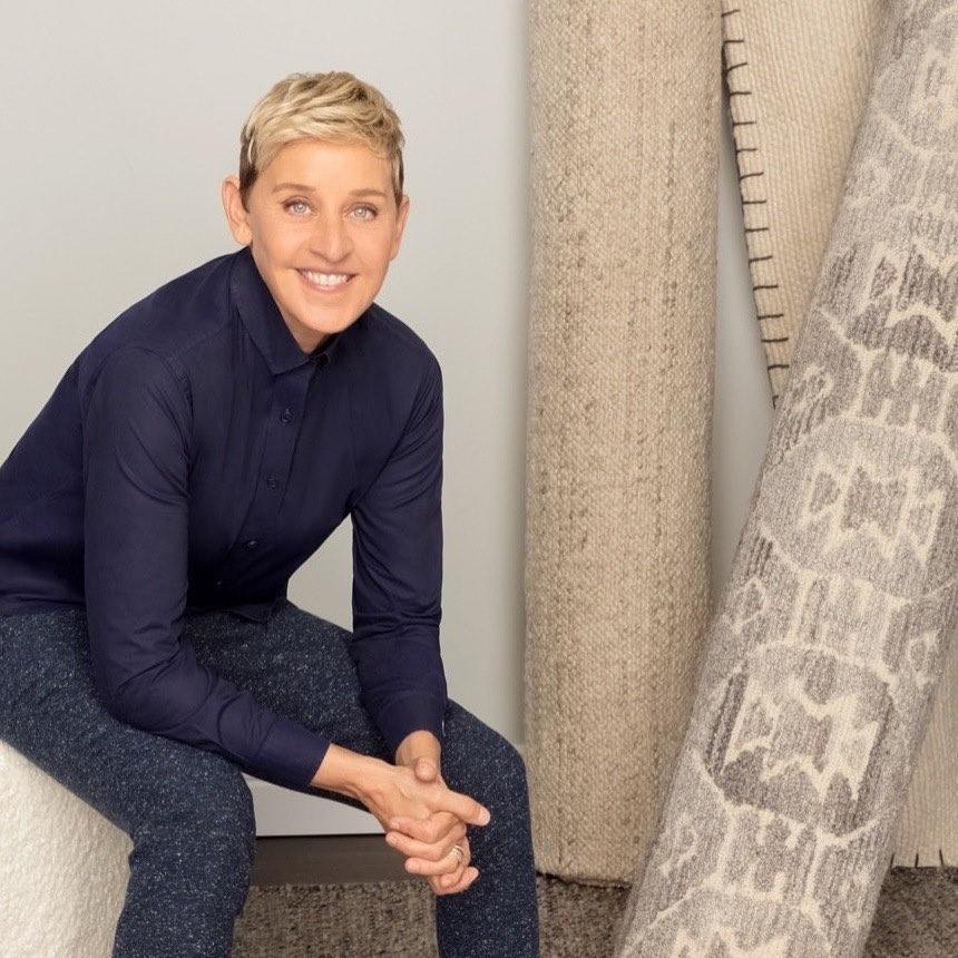 A photo of Ellen DeGeneres sporting a blue-black T-shirt and dark color denim pant.