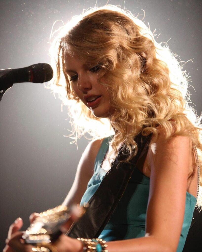 A photo showing Taylor Swift singing and playing the piano.