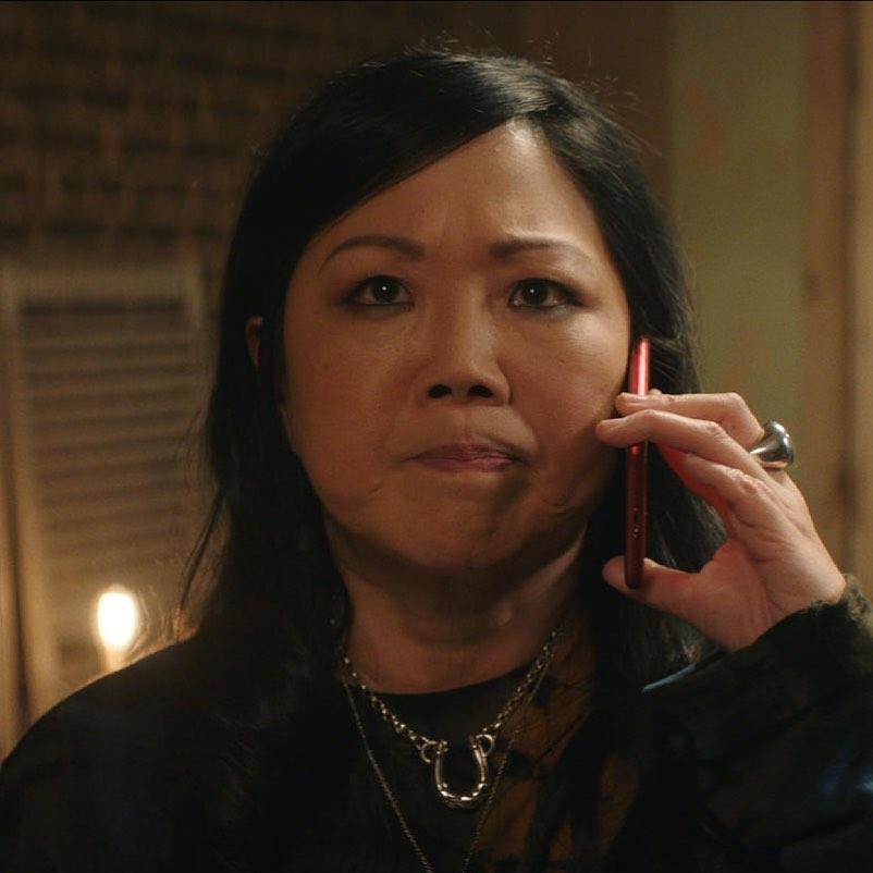 A lovely photo of Margaret Cho from the scene of a movie, seen making a phone call.