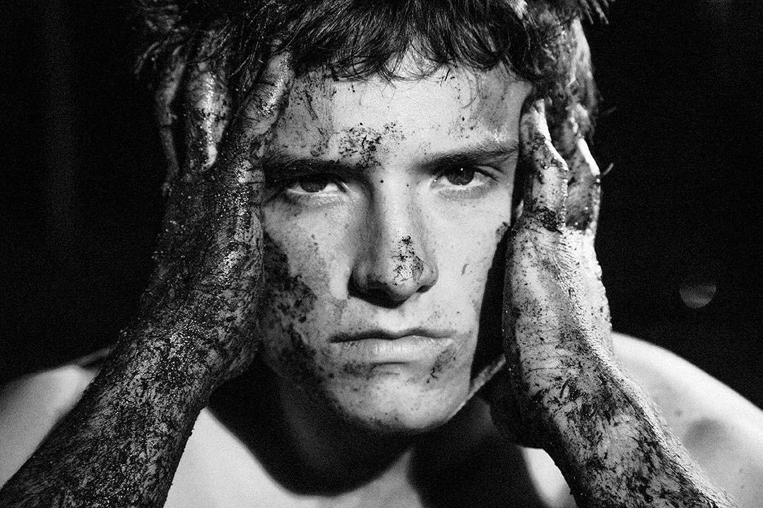 A black and white photo showing Josh Hutcherson covered in dirt.