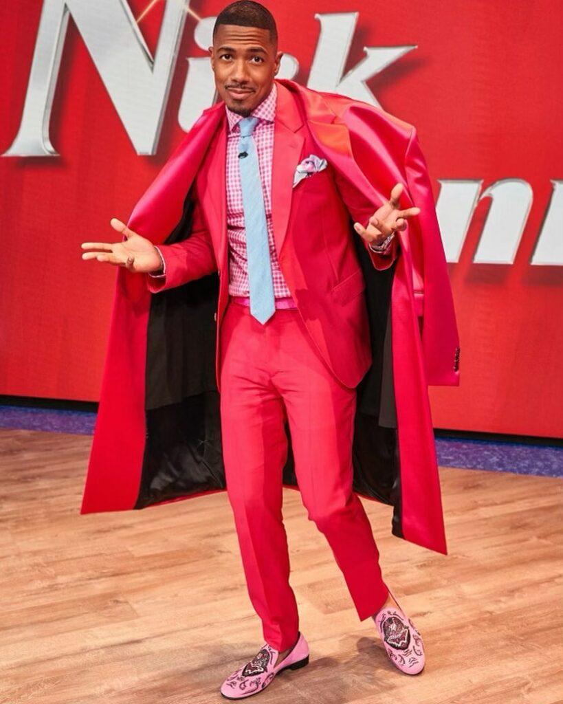 A lovely photo showing Nick Cannon in a red suit and coat paired with a white tie.
