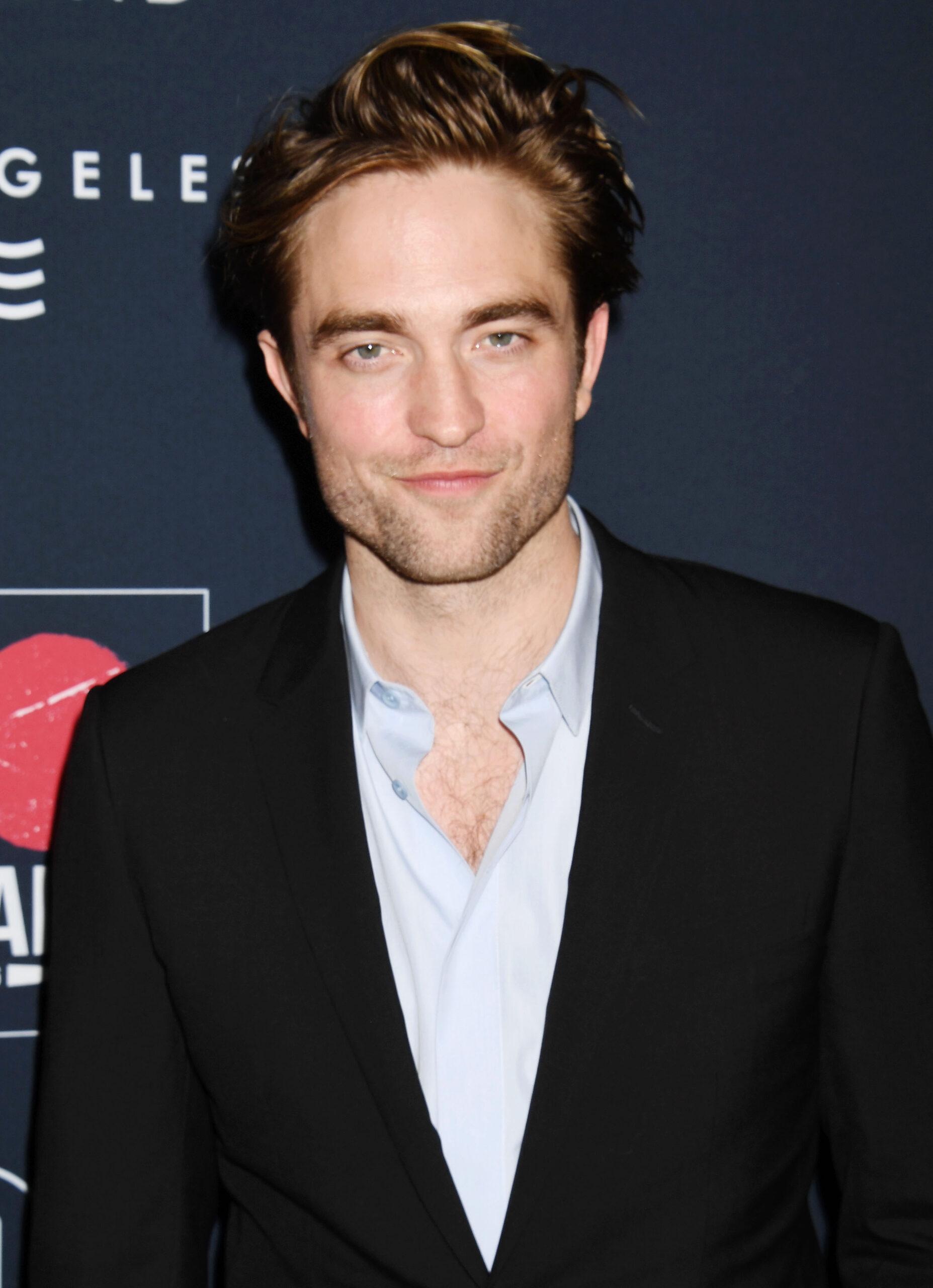 A photo showing Robert Pattinson in a black suit and white inner T-shirt.