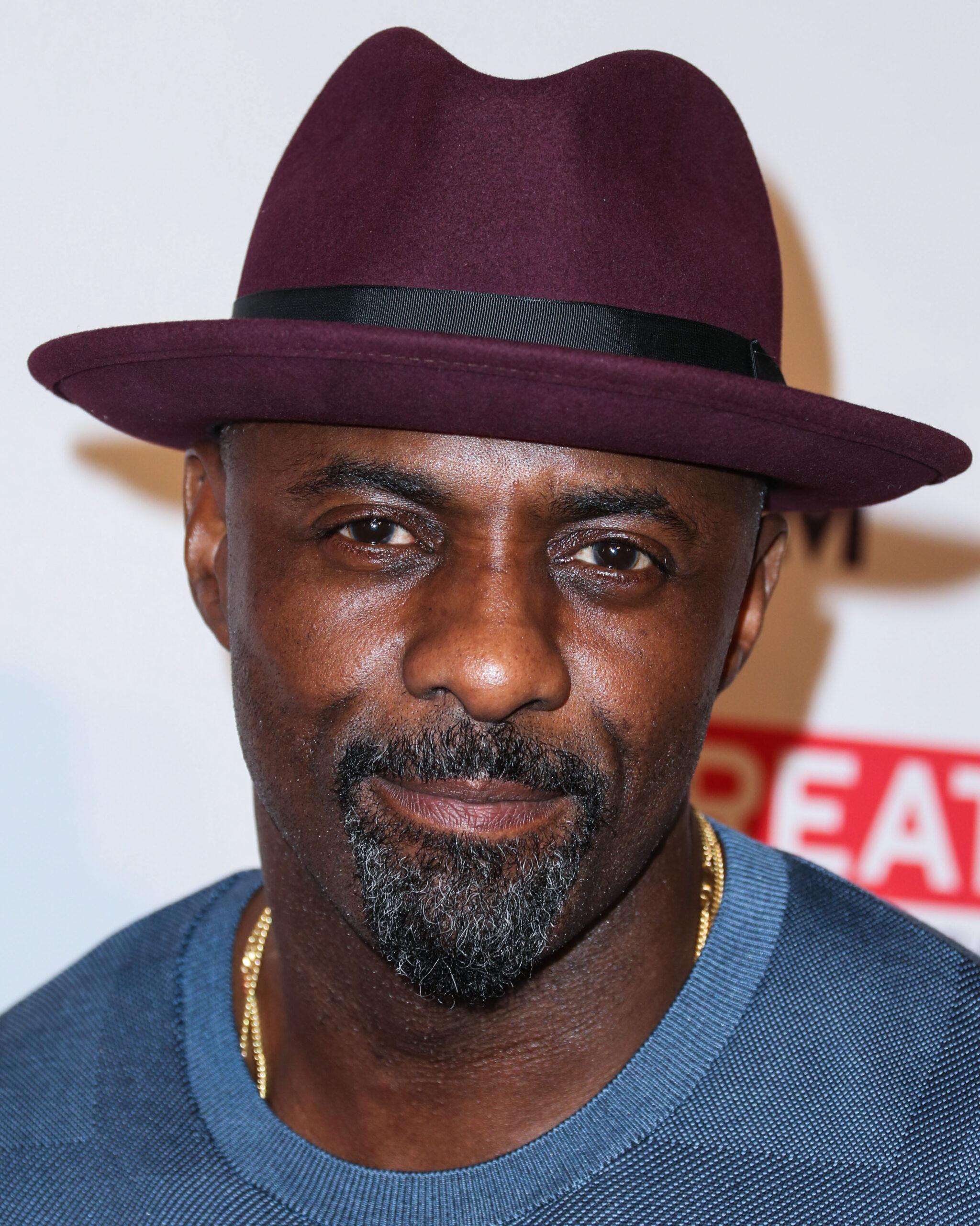 Idris Elba rocking a hat and blue shirt.