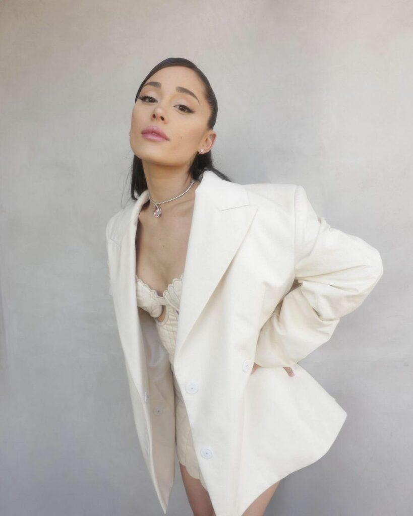 A photo showing Ariana Grande posing in a white suit.
