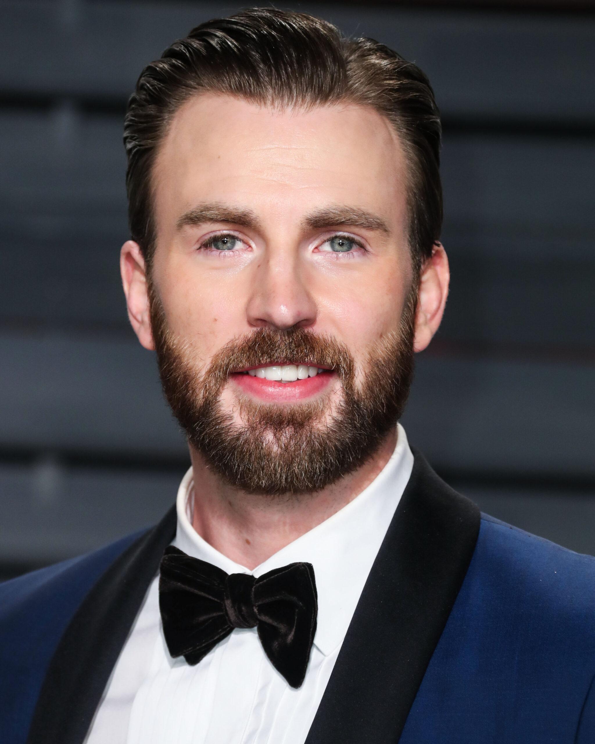 A photo showing Chris Evans sporting a dark blue suit, with a white inner T-shirt and black bow tie at an event.