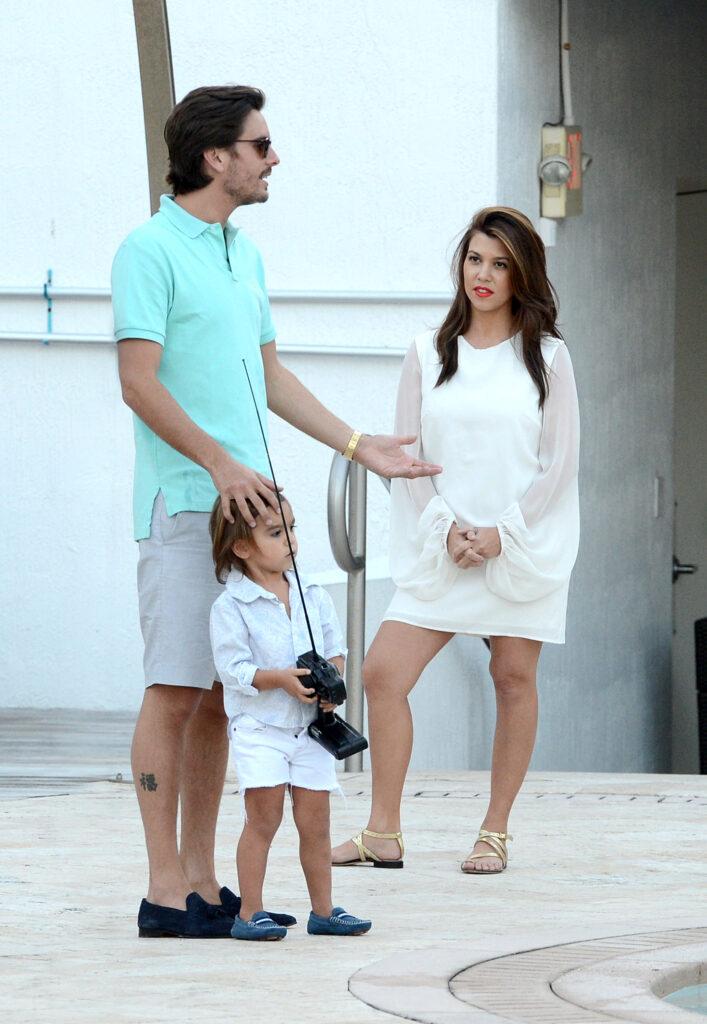 Kourtney Kardashian and Scott Disick with their son, Mason, play with a remote boat in the pool of the Eden Roc Hotel in Miami Beach