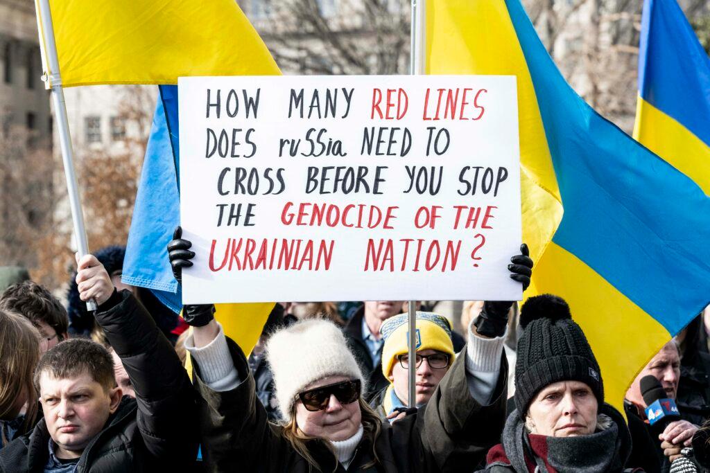 Washington, DC, United States: Ukrainian flags at a rally in front of the White House in support of Ukraine. 13 Mar 2022 Pictured: Washington, DC, United States: Woman holding a sign saying ''How many red lines does Russia need to cross before you stop the genocide of the Ukrainian nation?'' at a rally in front of the White House in support of Ukraine. Photo credit: ZUMAPRESS.com / MEGA TheMegaAgency.com +1 888 505 6342 (Mega Agency TagID: MEGA837908_003.jpg) [Photo via Mega Agency]