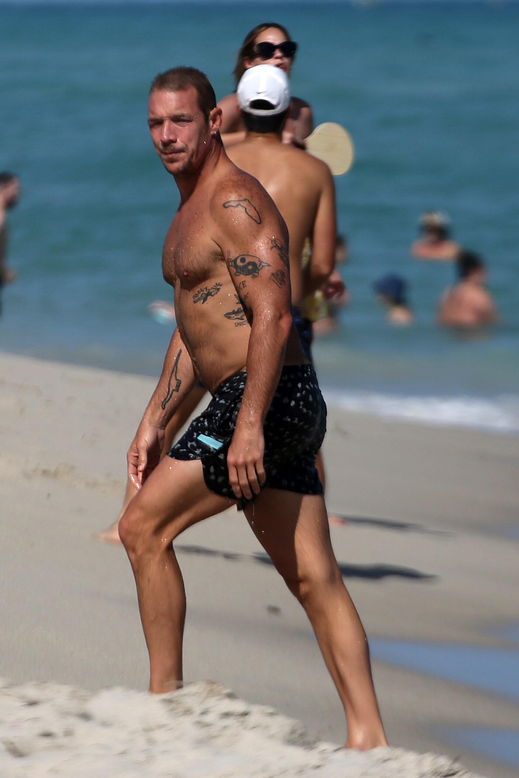 Shirtless DJ Diplo does some awkward looking exercises in the sand before chatting up billionaire developer Alan Faena on the beach in Miami