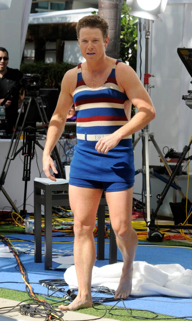 Billy Bush wears an old fashion bathing suit in the pool while taping Access Hollywood in Miami Beach