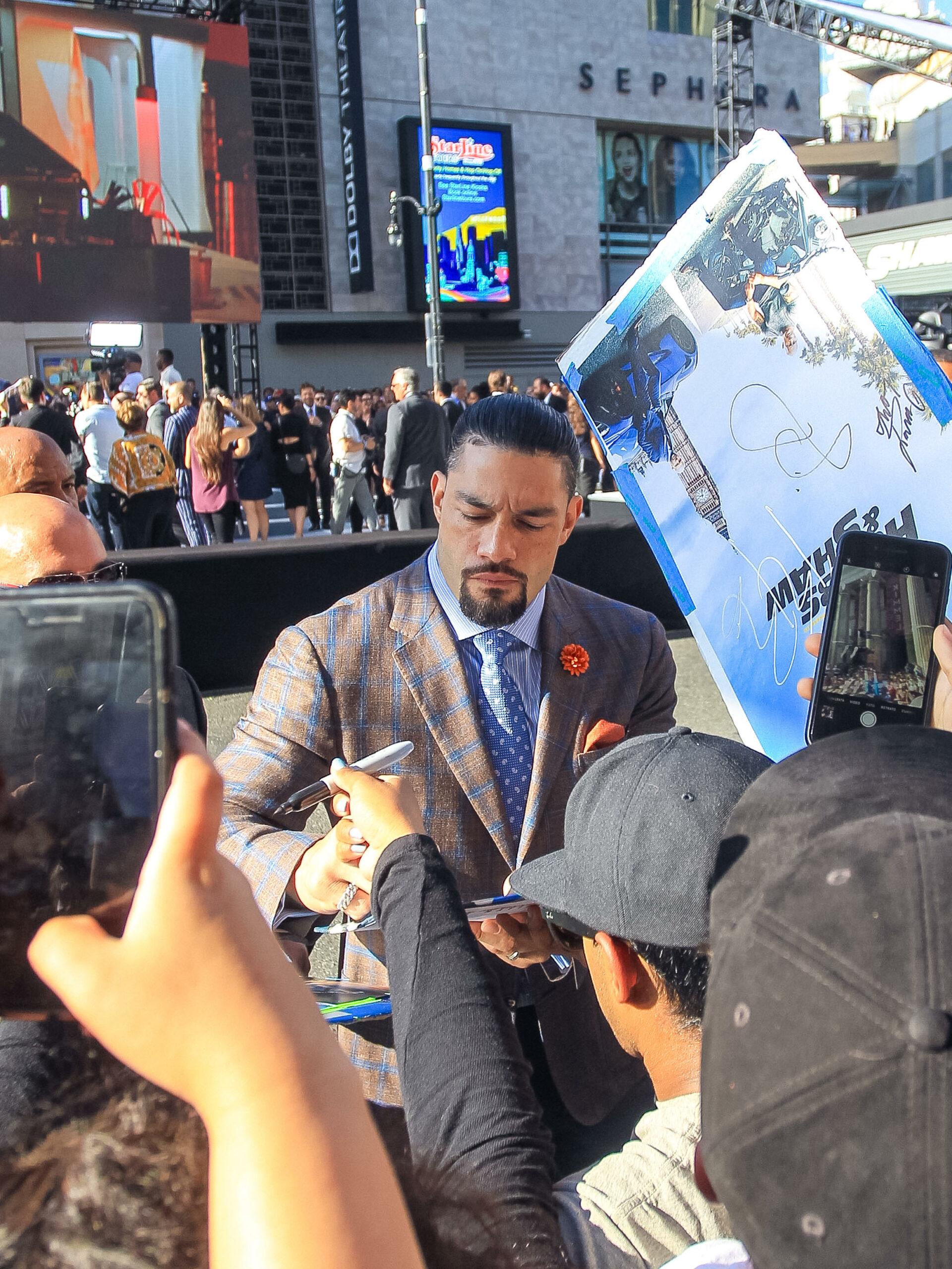 Roman Reigns signing autographs at premiere.