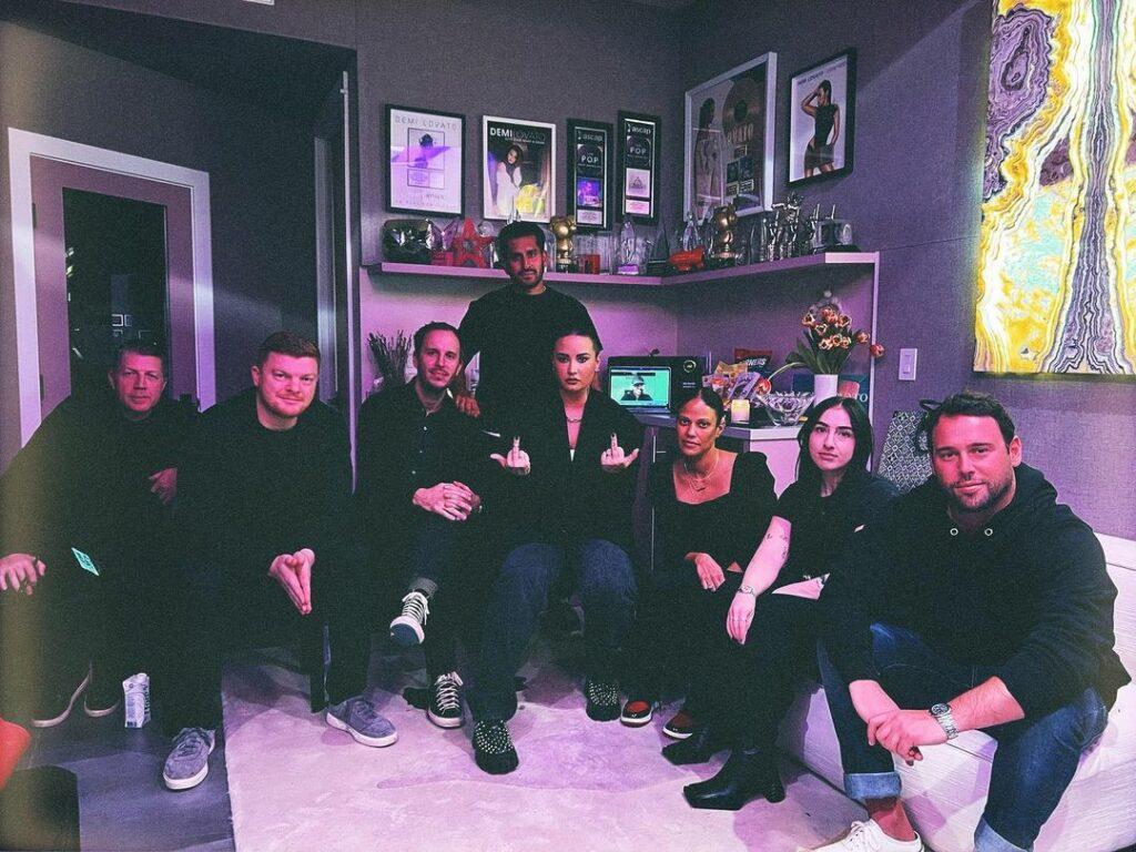 Demi Lovato, Scooter Braun, and their team posing for the camera.