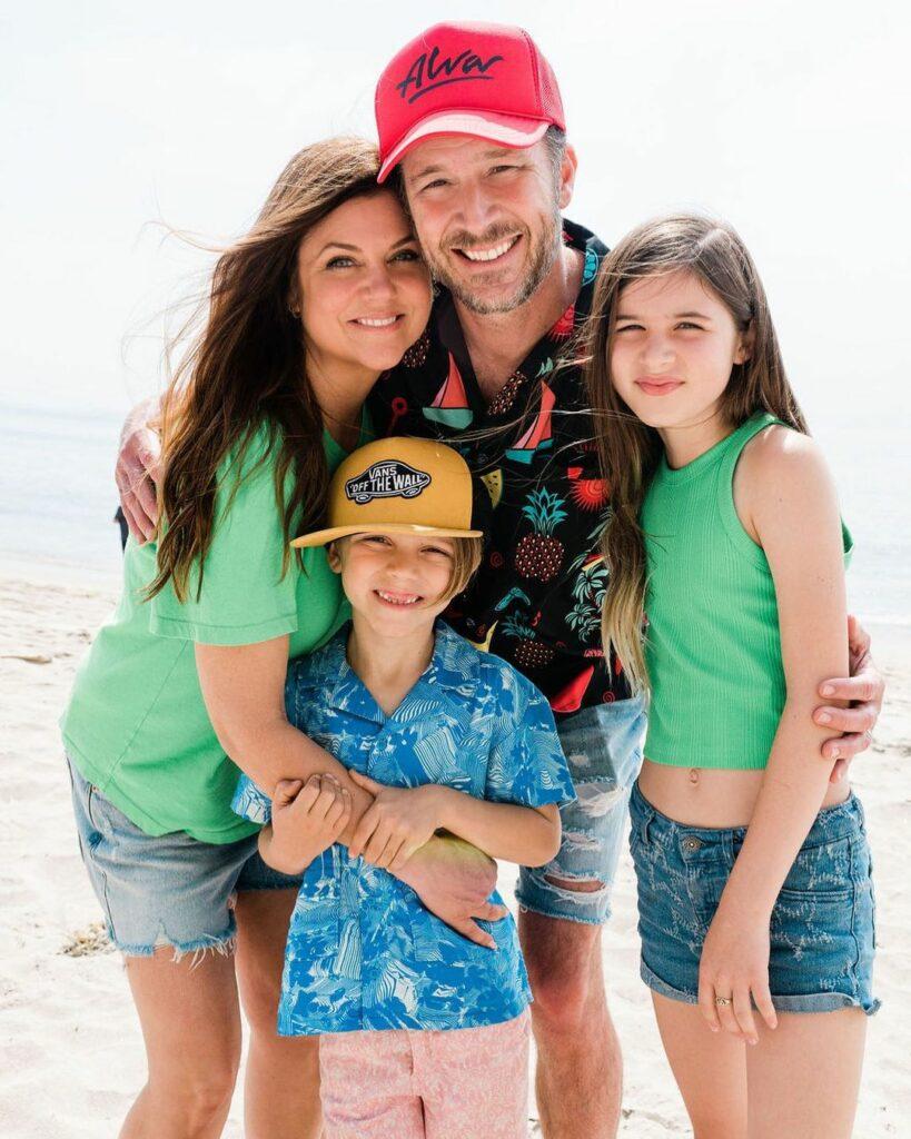 Tiffani Thiessen, Brady Smith, and their kids smiling.