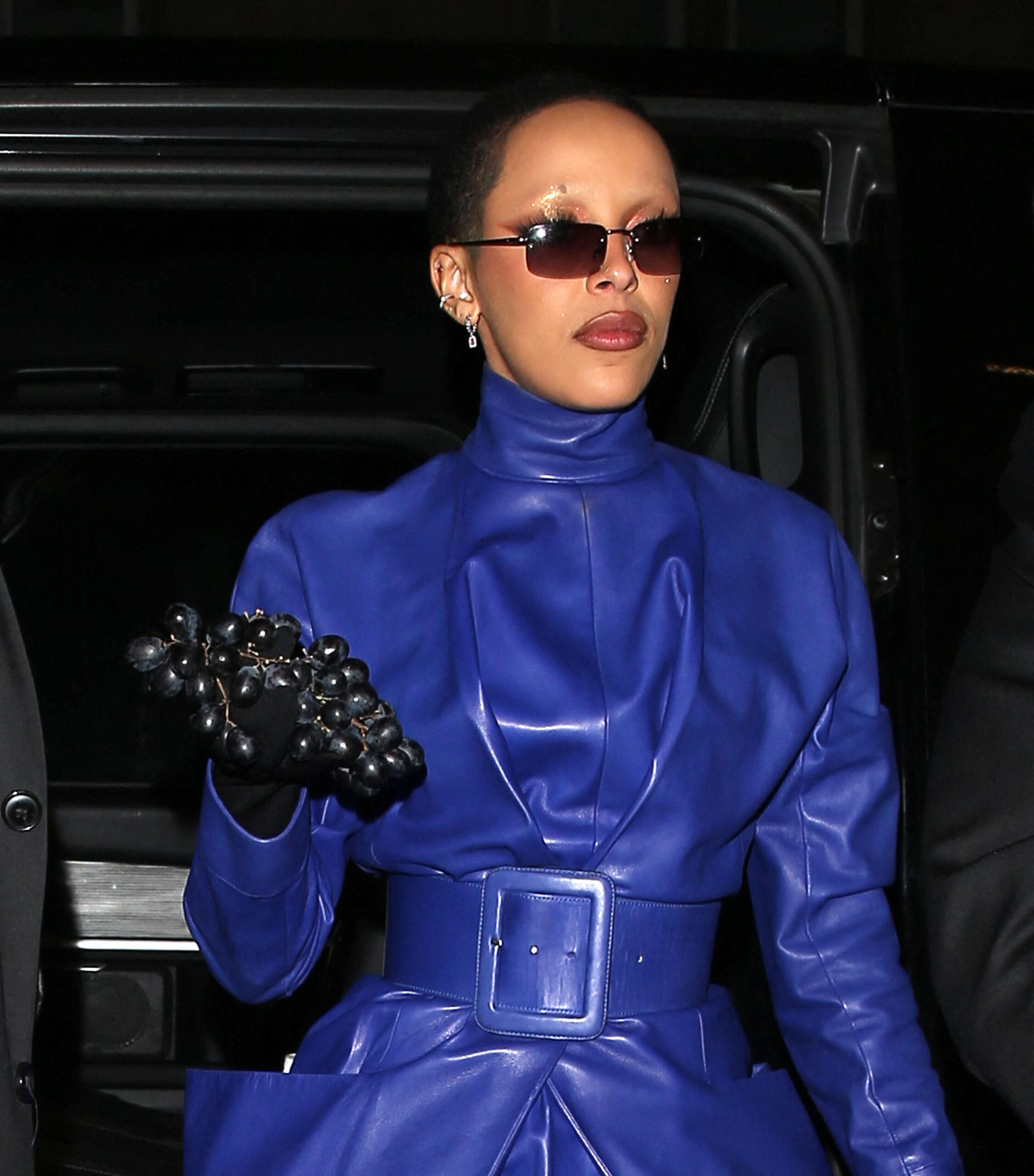 Doja cat wears a Blue leather outfit with a bunch of Dark Colored Grapes in her hand at Jean Paul Gaultier in Paris