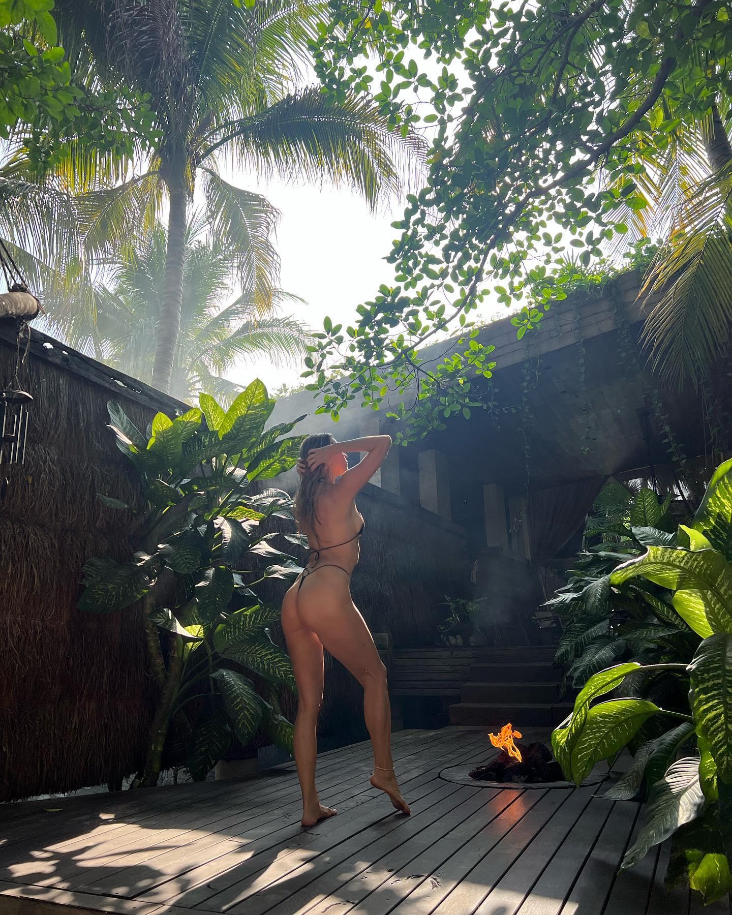 Jenna Lee in the jungle in a black thong bikini