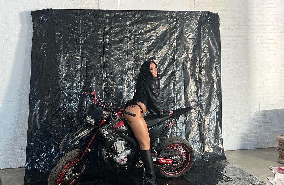 Lourdes Leon standing a motorcycle.