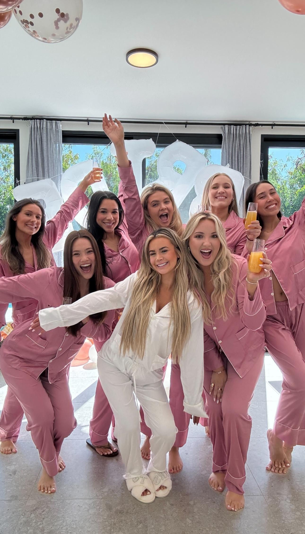 Emily Elizabeth in white pyjamas posing with her friends in pink pyjamas at her bridal party in the Turks and Caicos.
