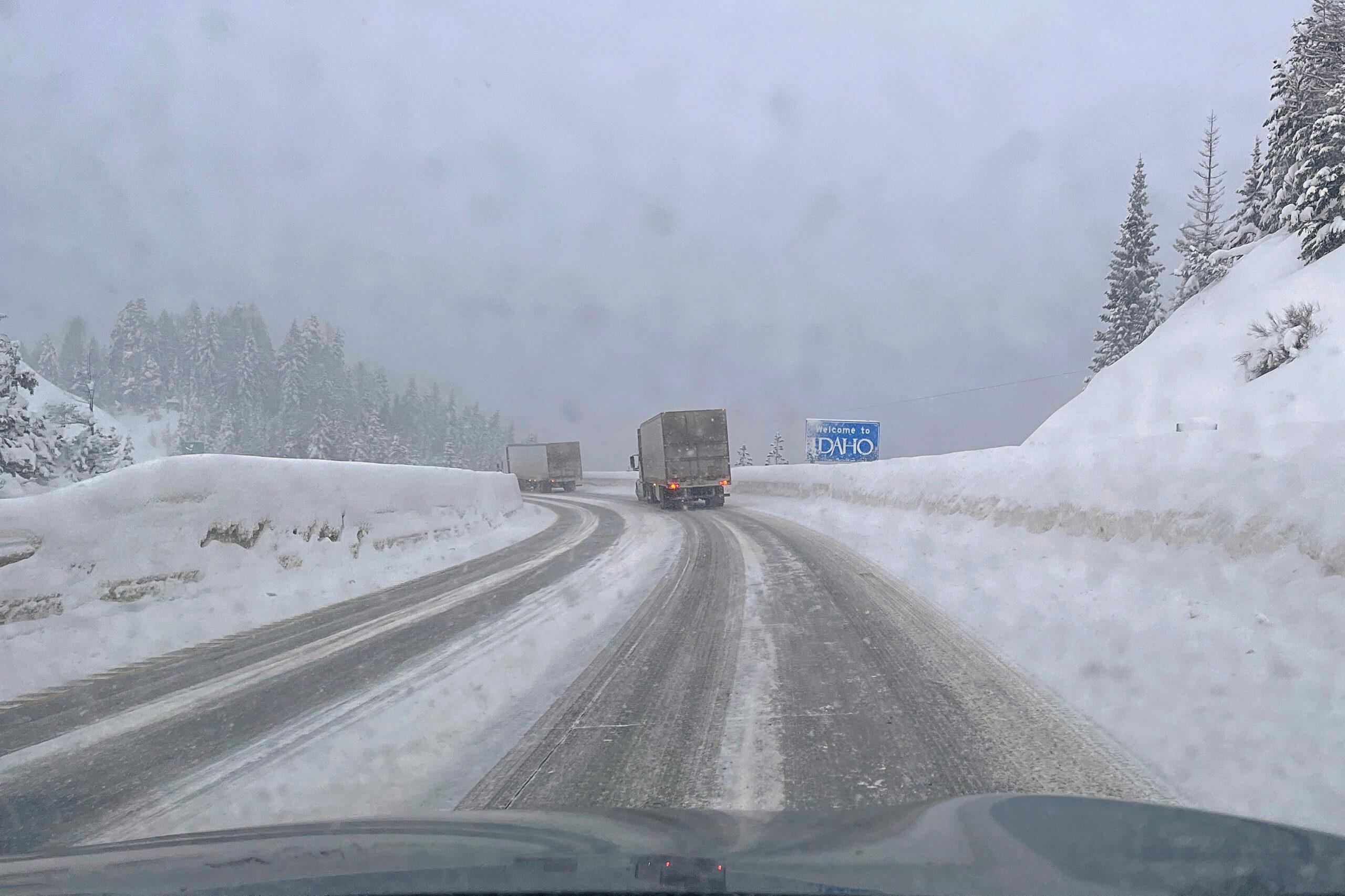 Snowy winter driving conditions entering Idaho over mountain pass along Interstate 90