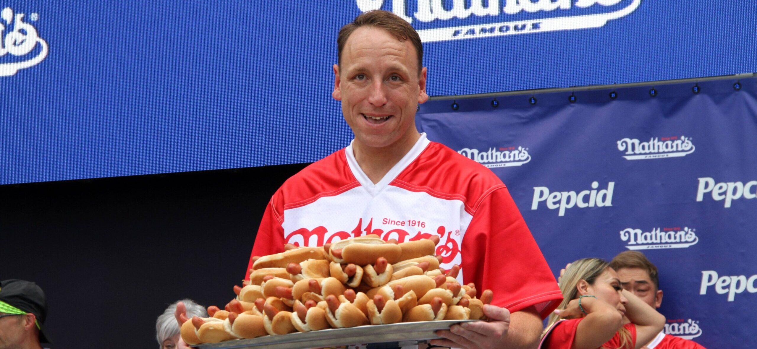 Joey Chestnut holding a plate of hot dogs