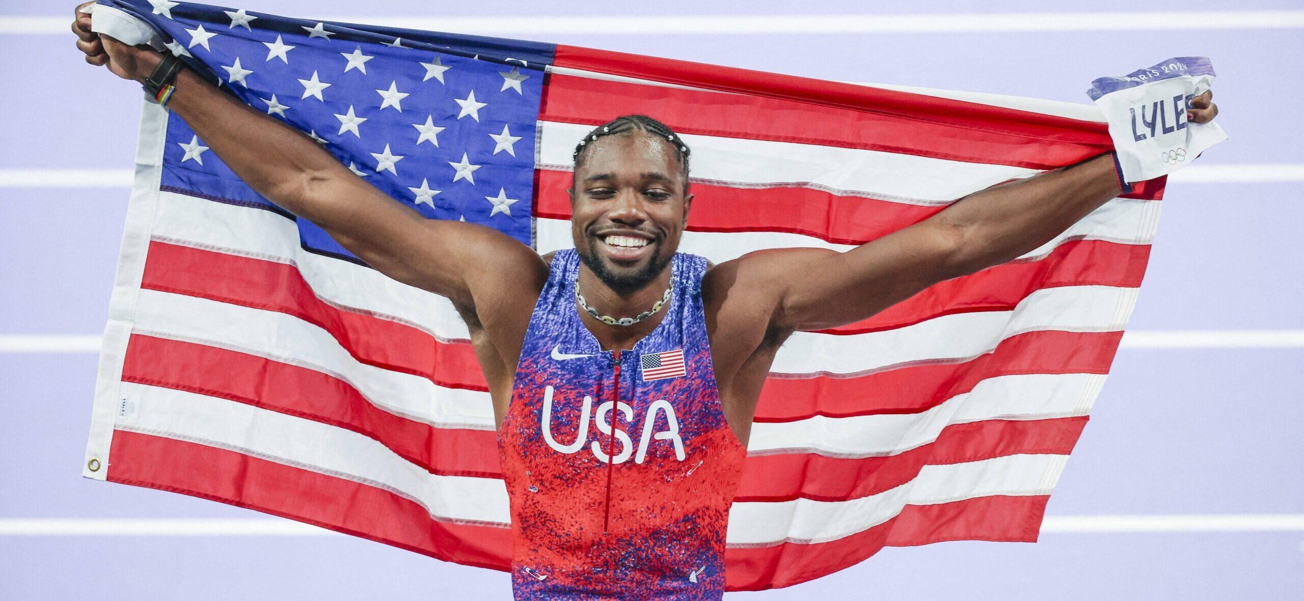 Noah Lyles celebrating at the 2024 Paris Olympics with American Flag