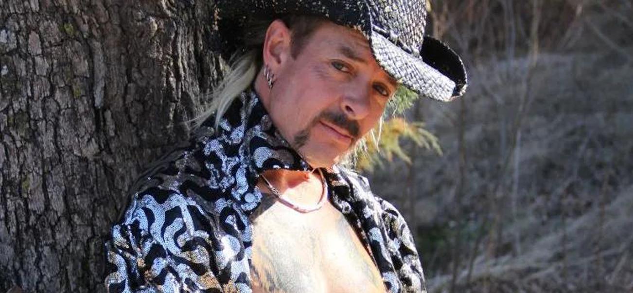 Joe Exotic striking a pose against a tree