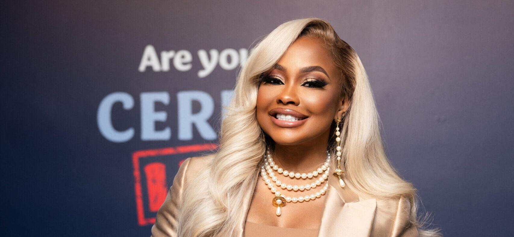 Phaedra Parks posing in a gold suit with blonde hair smiling for a picture.