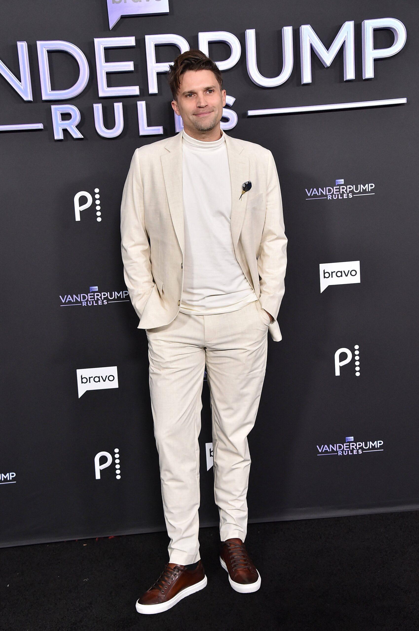 Tom Schwartz posing in white on the red carpet for a 'Vanderpump Rules' event. 