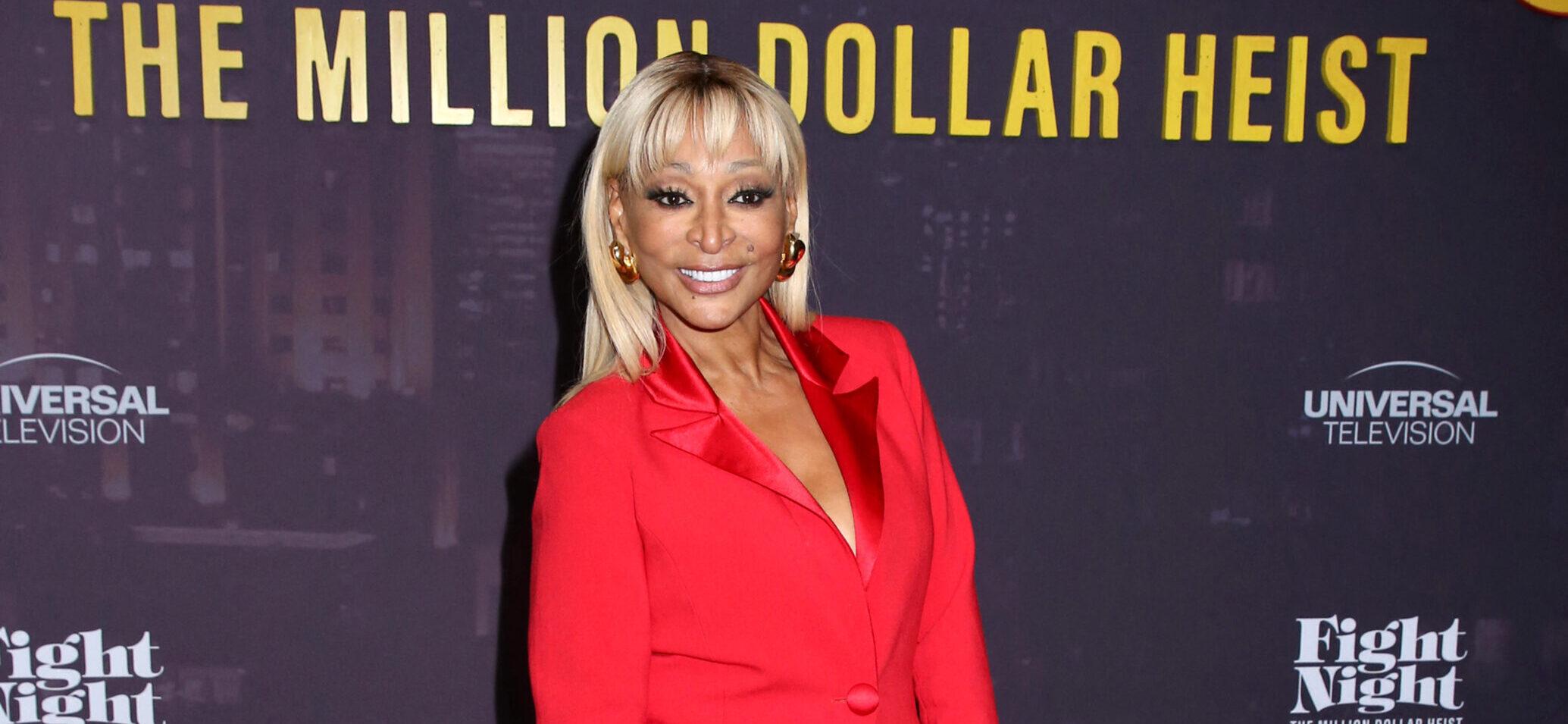 Karen Huger posing in a red dress on the red carpet.