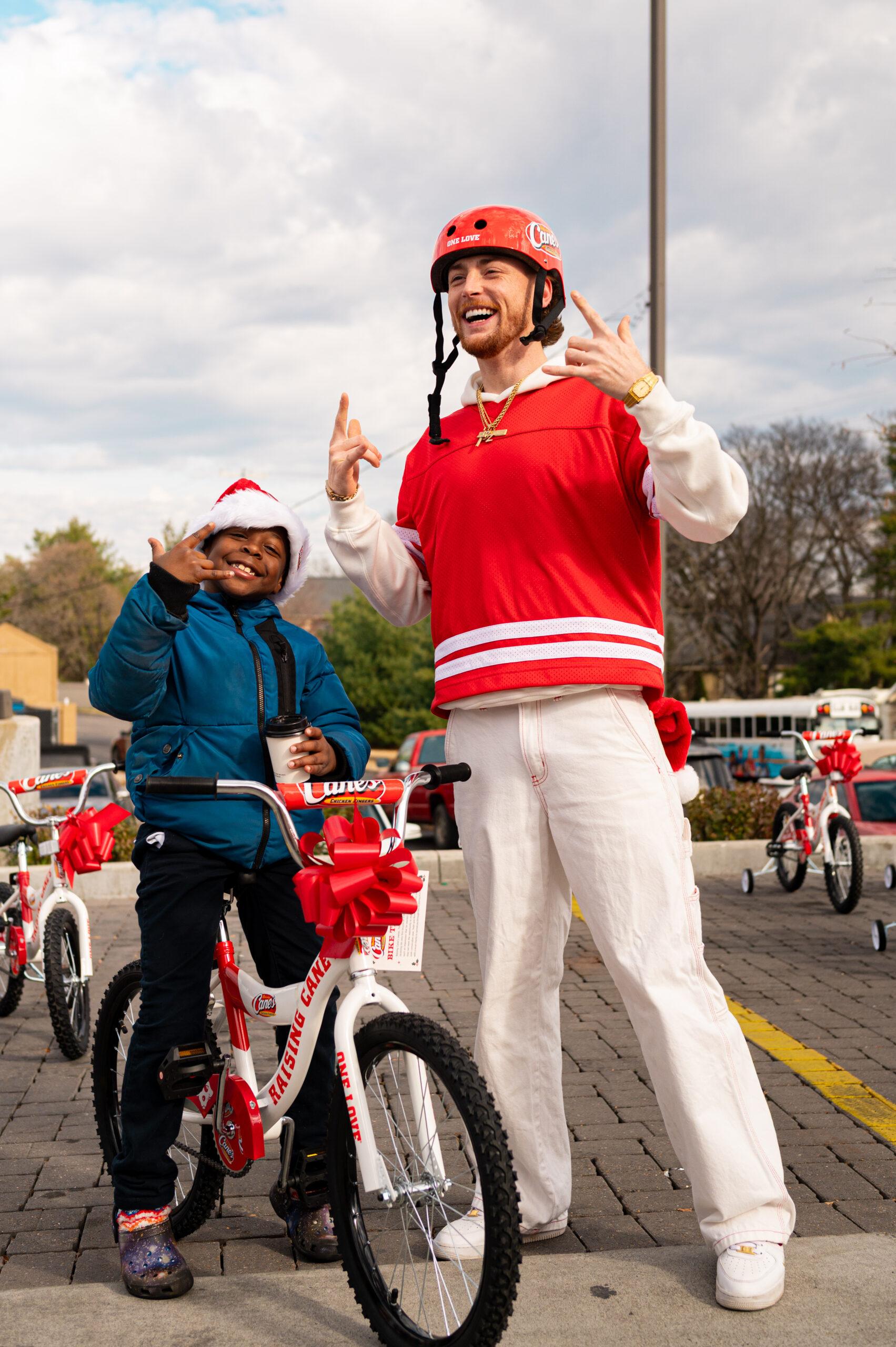 Bailey Zimmerman at Raising Cane's event with child for bike giveaway