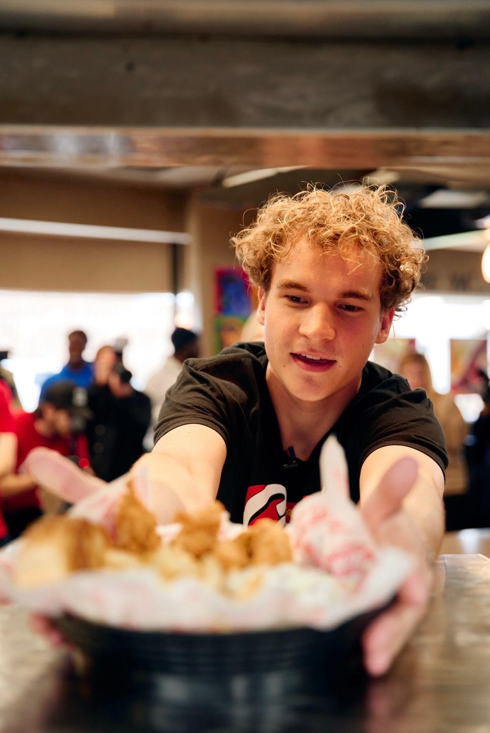 Aiden Ross serving Raising Cane's chicken