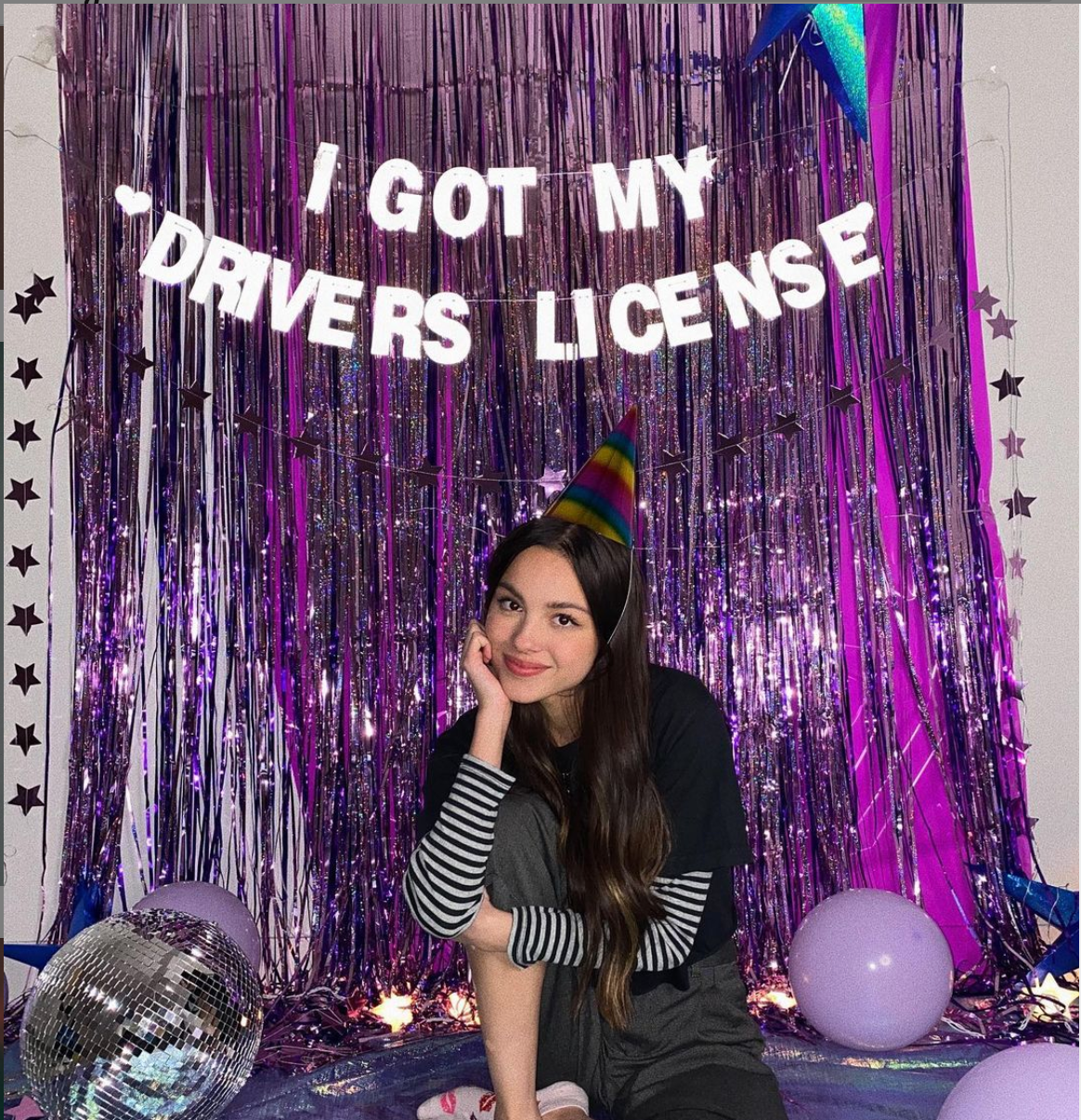 Olivia Rodrigo in front of streamers & a driver's license sign