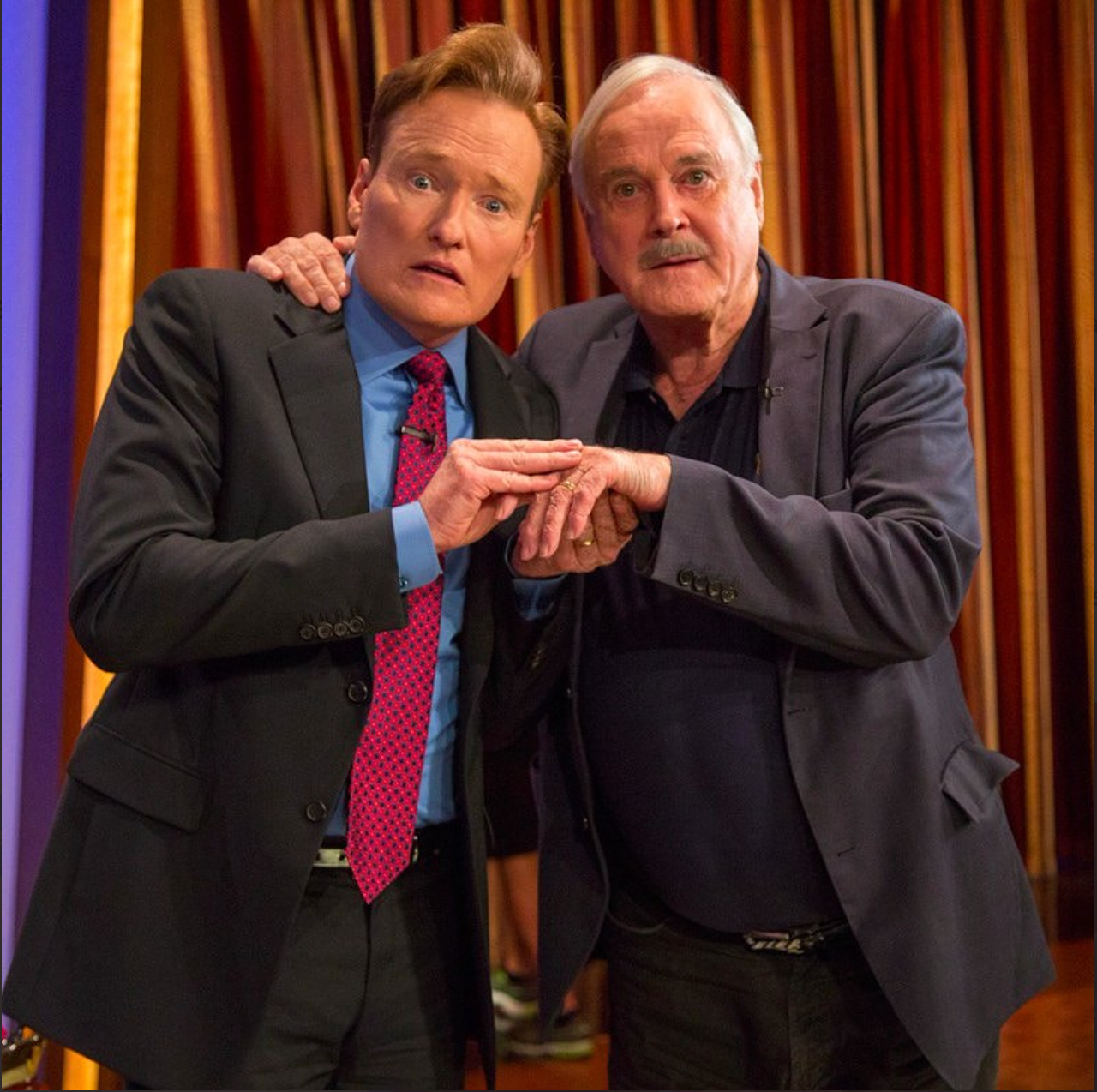 Conan O'Brien and John Cleese holding hands