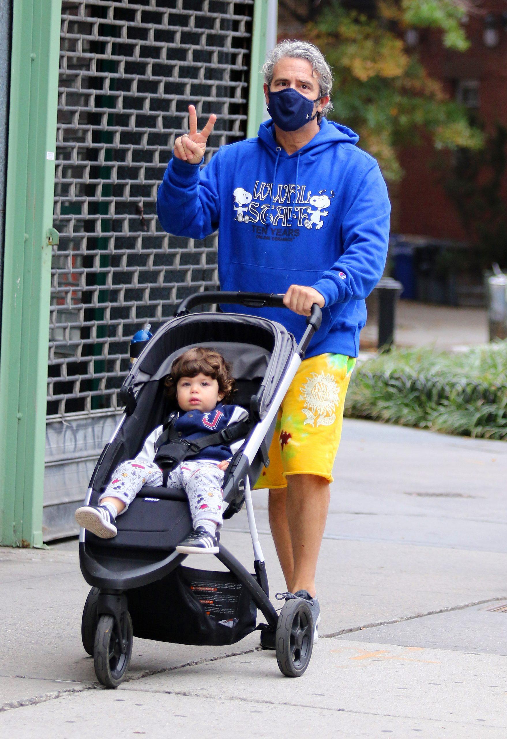 Andy Cohen gives the peace sign and a thumbs up while on a stroll with his son Benjamin in NYC