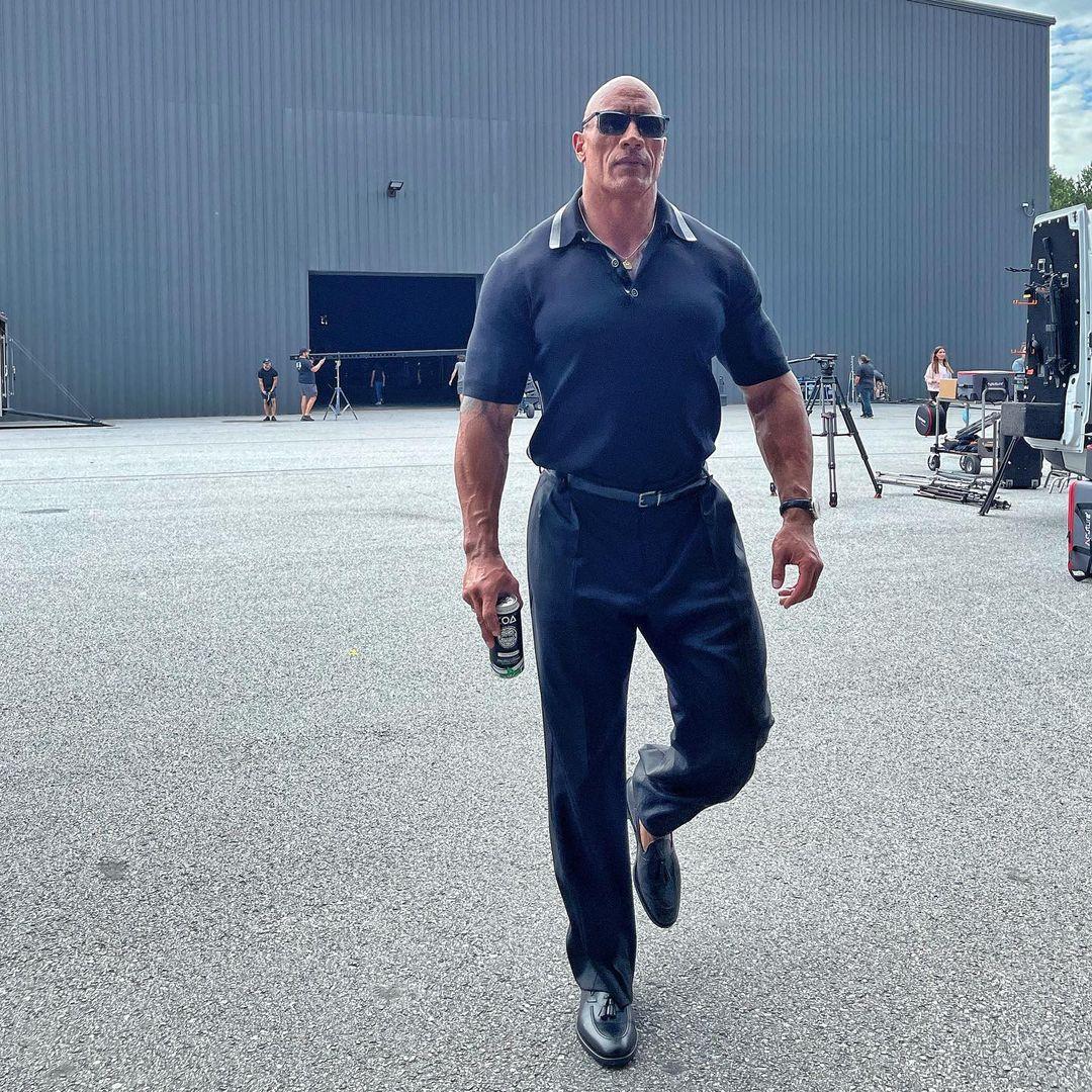 A photo of Dwayne Johnson wearing a polo shirt and pant.