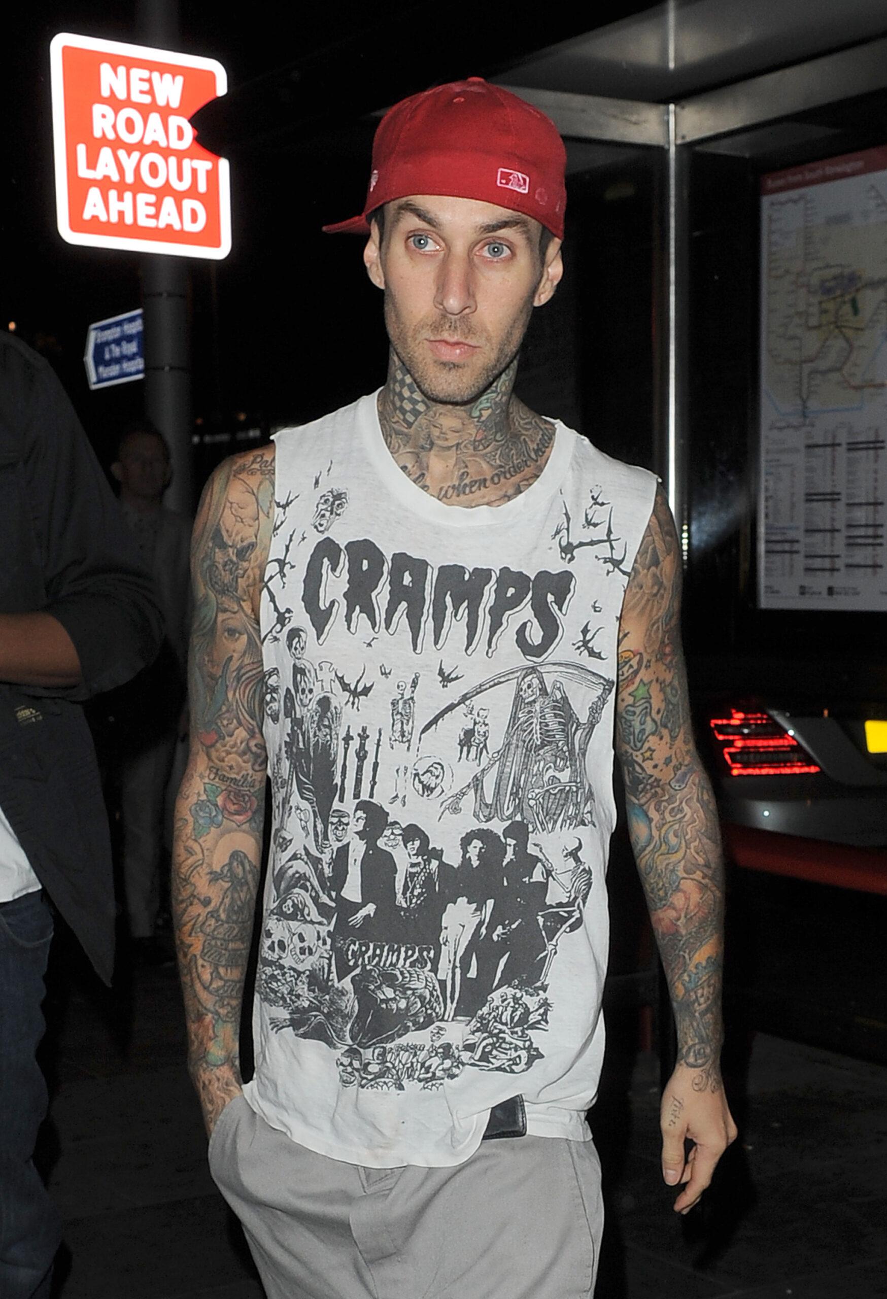 Travis Barker of Blink-182 arriving at Boujis nightclub in Kensington He wore a Cramps vest baggy grey shorts and a red baseball cap