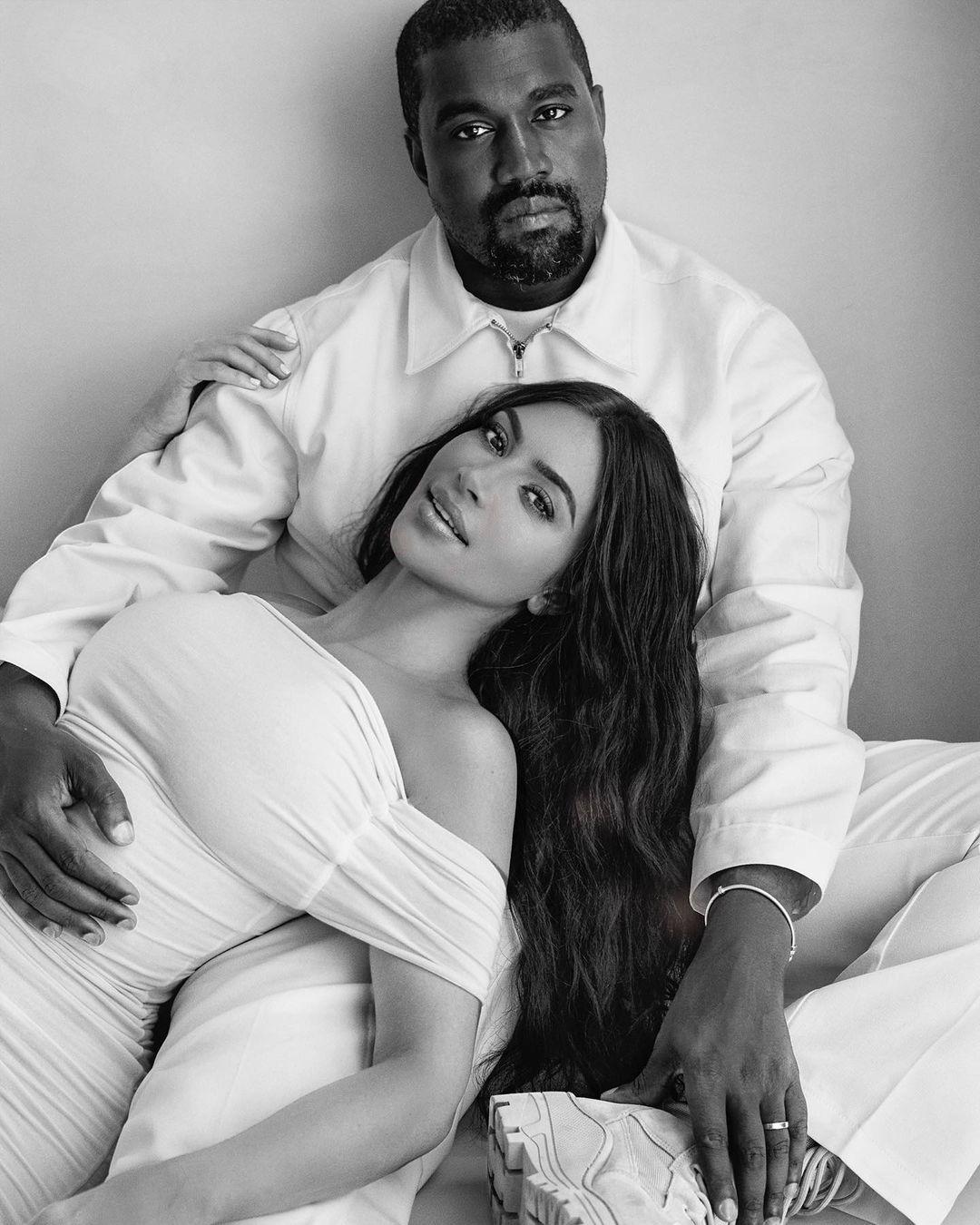 A black and white themed photo showing Kanye West and Kim Kardashian in white outfits.