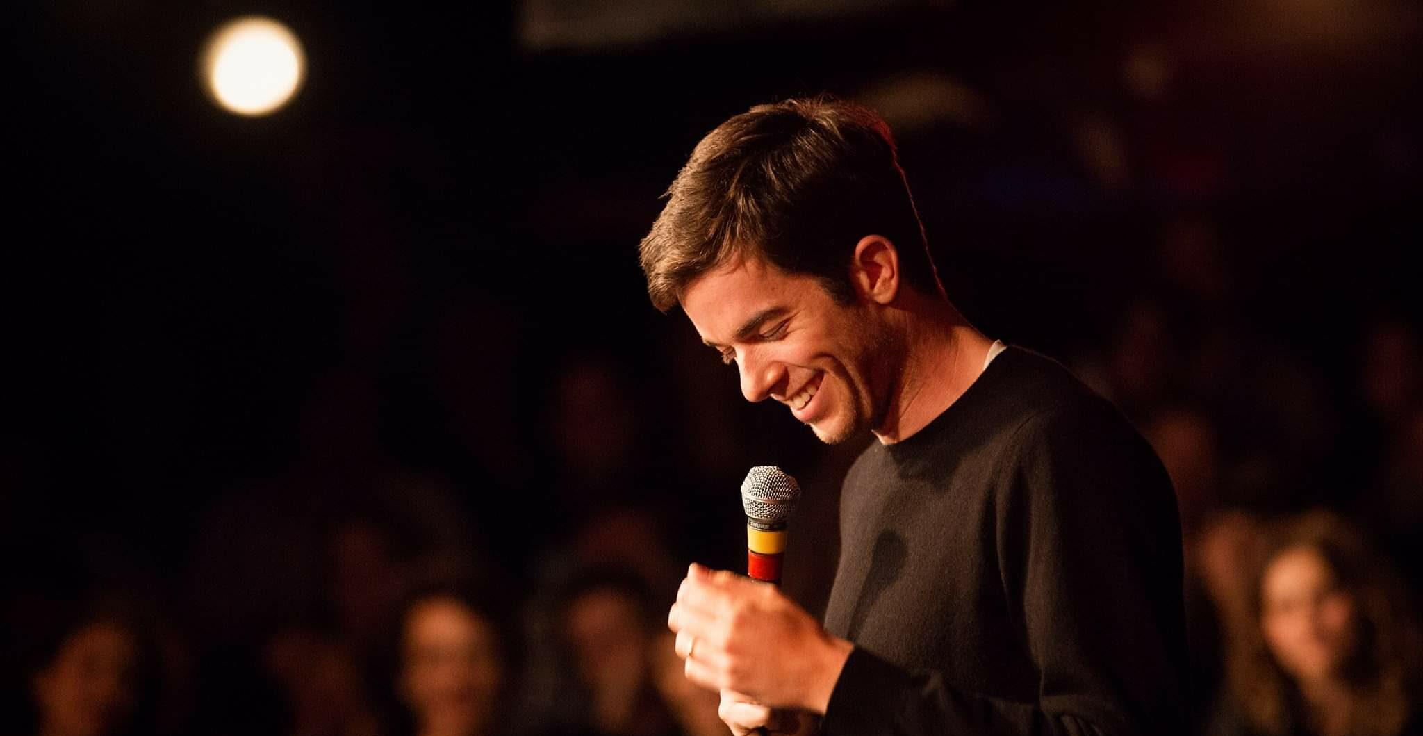 A photo showing John Mulaney telling jokes to a vast audience
