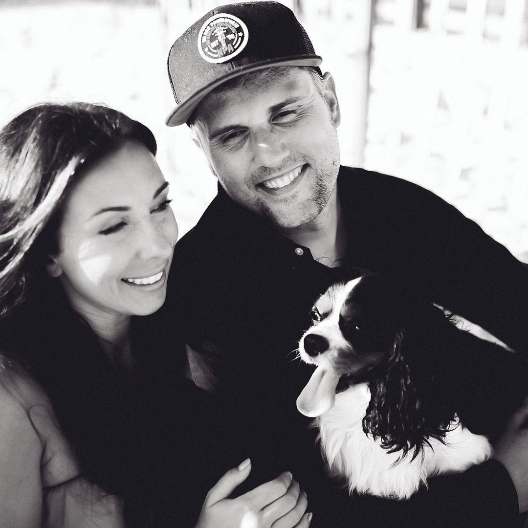 A black and white themed photo of Mackenzie, Ryan Edwards, and their dog.