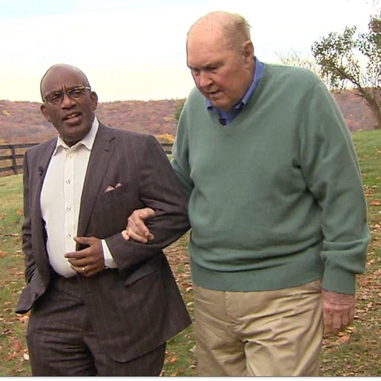 A photo of Al Roker and Willard Scott holding hands while walking on a field.