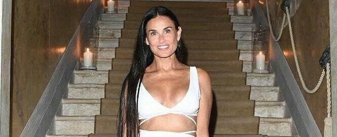 A photo showing Demi Moore at the edge of a staircase, sporting a white dress.