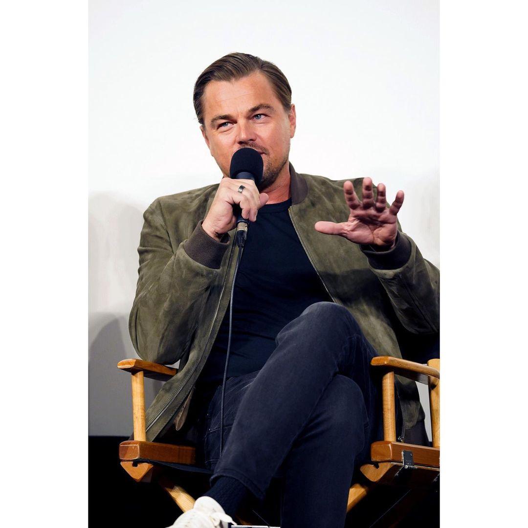 A photo showing Leonardo DiCaprio sitting and talking through a microphone