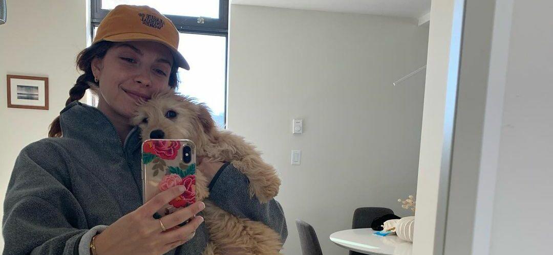 A photo showing Paige Spara in casual clothes, taking a selfie with her furry friend.