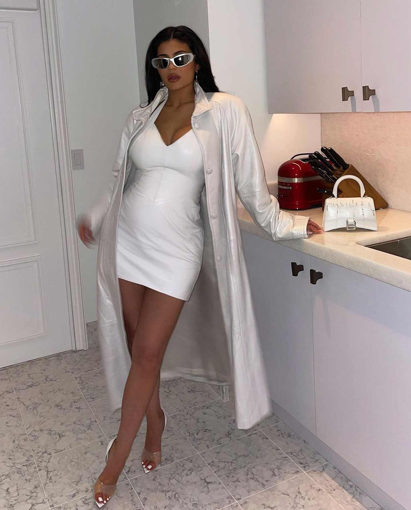 Kylie Jenner in a white latex outfit with her baby bump showing.