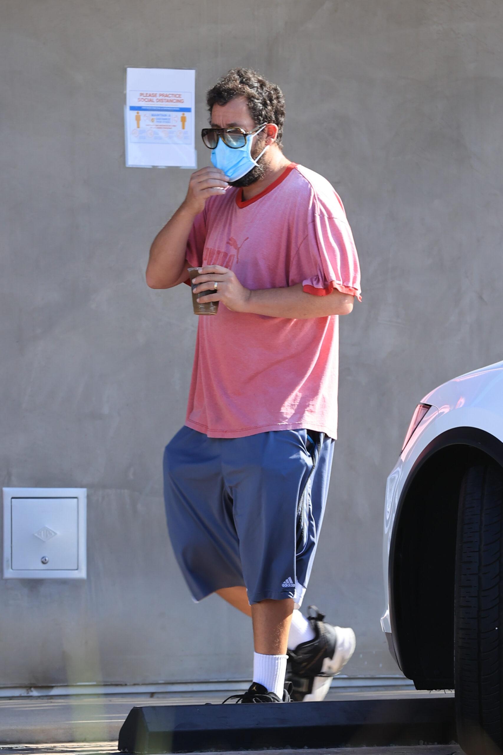 Adam Sandler struggles with sunglasses and mask combination as he grabs his morning coffee