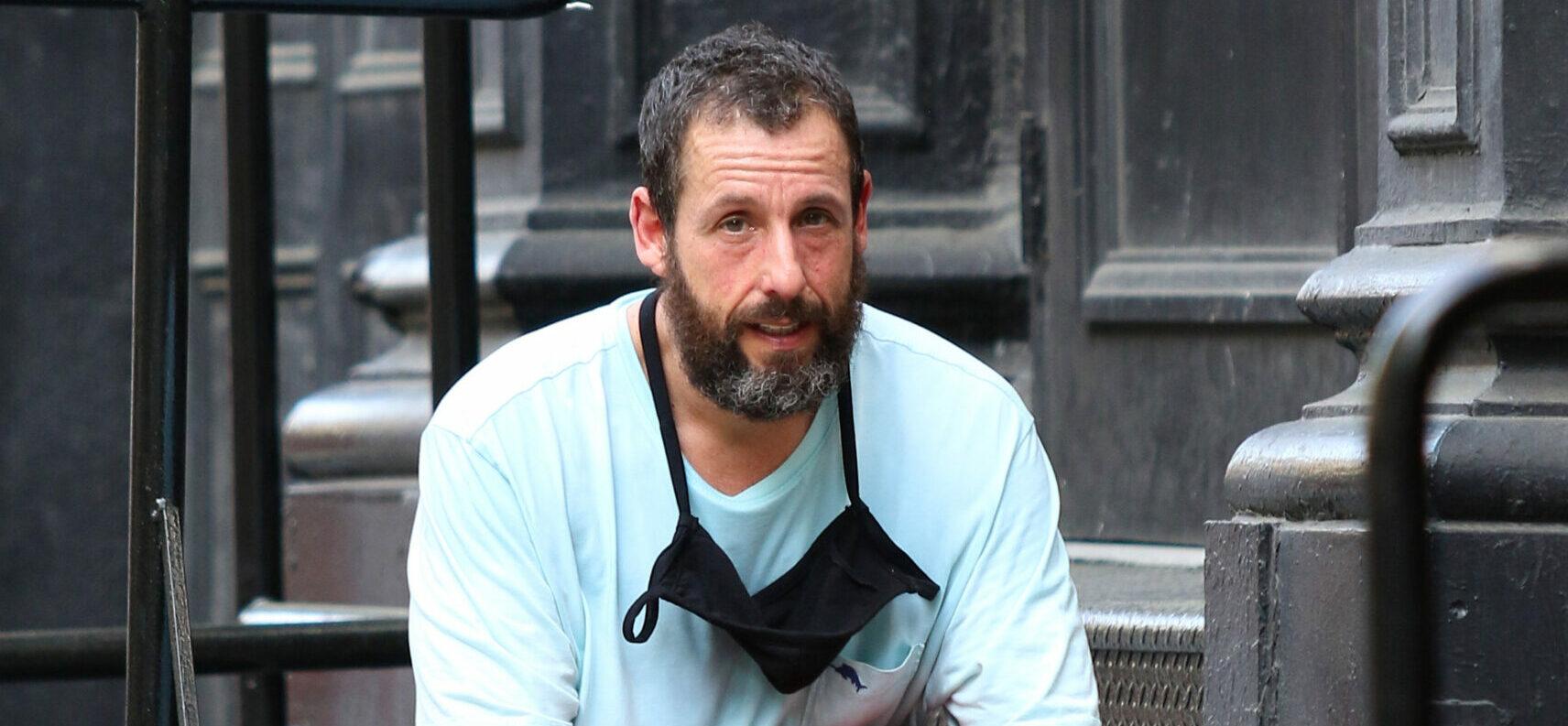 Adam Sandler holds a basketball and sits down to rest after a game in NYC