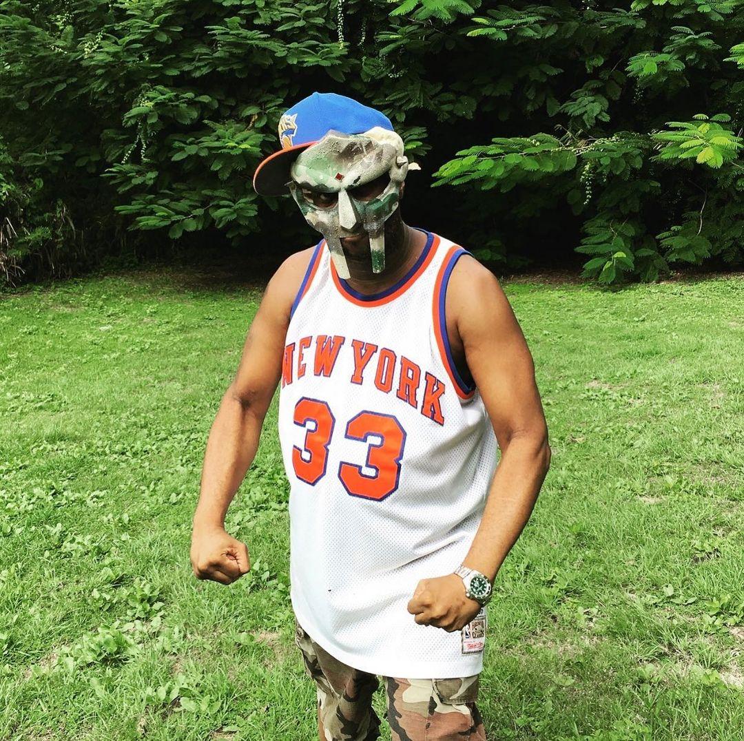 A photo showing MF Doom in a Yorkers vest and a metal mask.