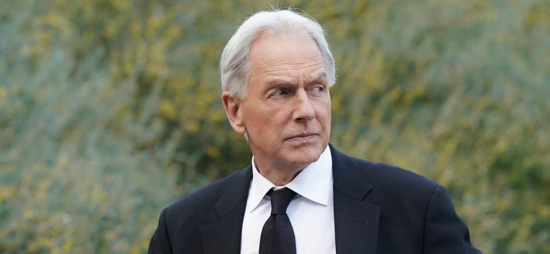 An amazing photo of Mark Harmon sporting a black suit with a white T-shirt and black tie.