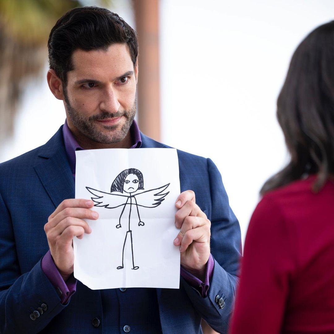 A photo showing Tom Ellis holding a drawing of an angel with wings.