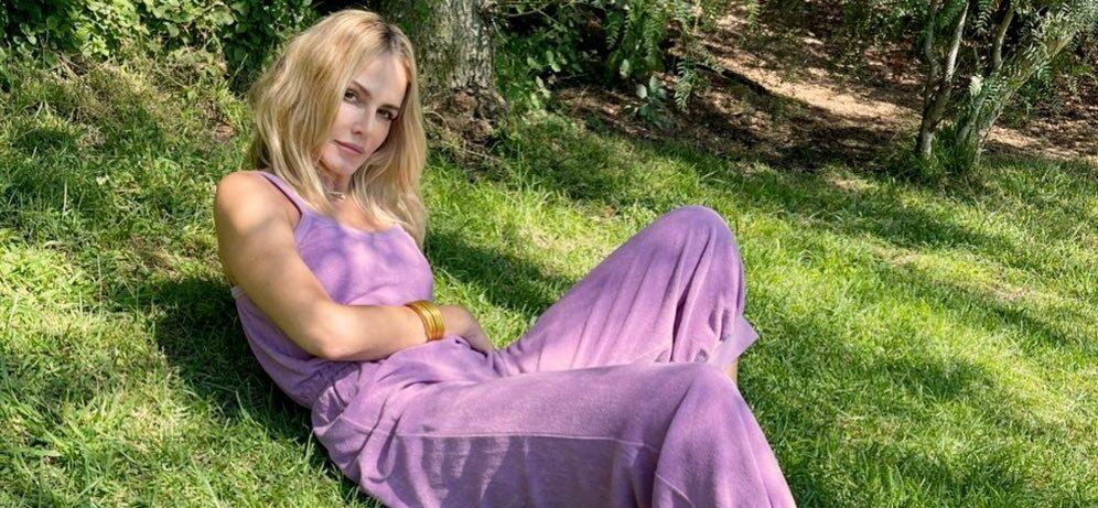 A photo showing Monet Mazur in a pink jumpsuit laying on a green grass.