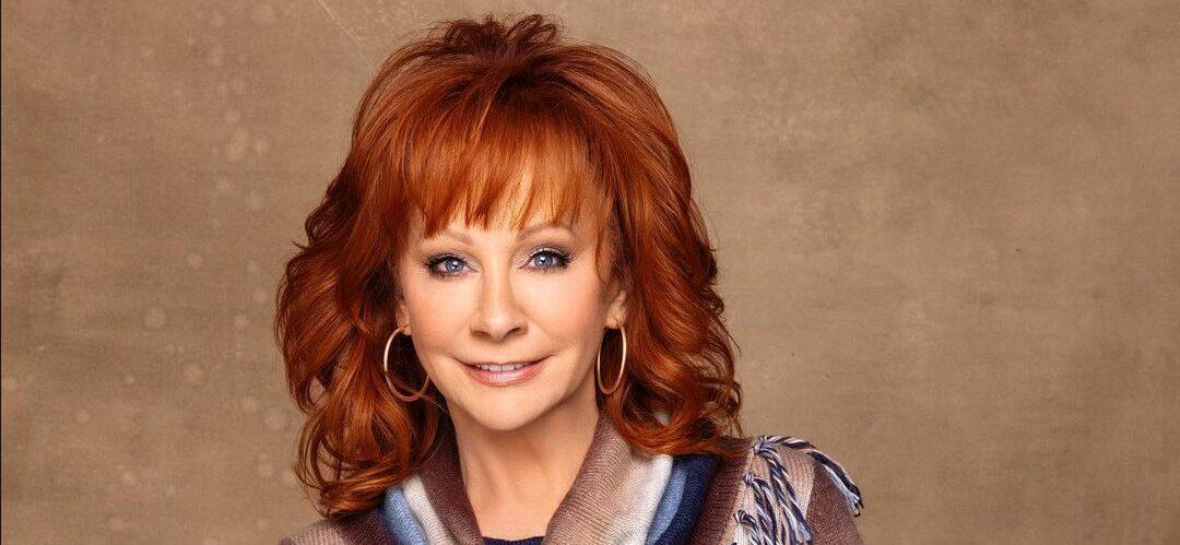 A beautiful photo showing Reba McEntire in a multicolored outfit and her signature curled red hair looks incredible.